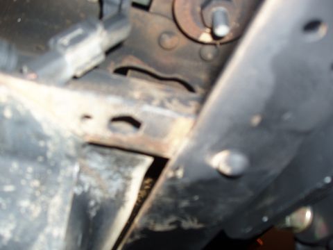 1994 Ford Bronco - A close-up view of the vehicle's undercarriage, showing frame and suspension components with signs of wear and rust.