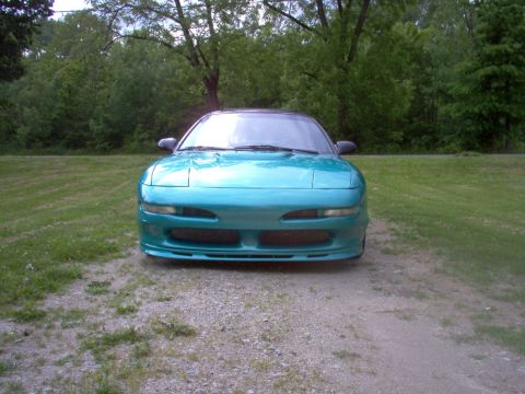 1993 Ford Probe - A teal 1993 Ford Probe is shown from the front, parked on a gravel surface with a wooded area behind it.