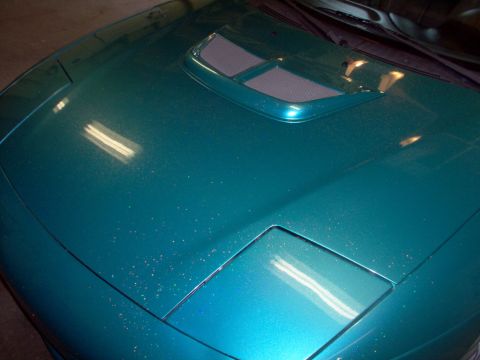 1993 Ford Probe - Close-up of a teal car's hood, showing a prominent air scoop and part of a headlight.