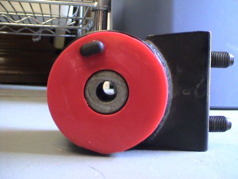 1997 Ford Probe - Close-up of a red bushing attached to a black metal bracket, with the Supermotors.net logo visible at the bottom.