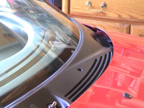 1997 Ford Probe - Close-up view of a red car's windshield cowl and surrounding bodywork, black trim and ventilation grilles. The Supermotors logo is present…