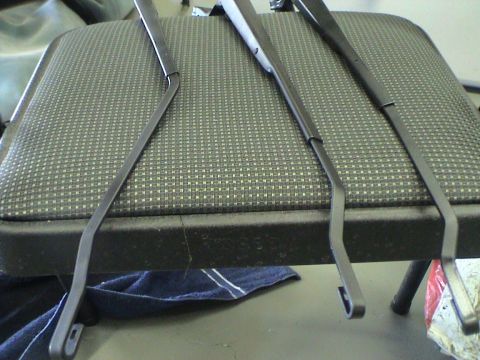 1997 Ford Probe - Three windshield wiper arms are laid out on a textured seat, with a blue towel visible below.