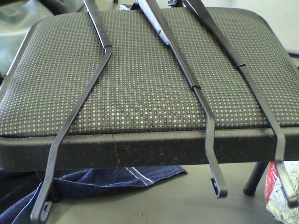 Three windshield wiper arms resting on a patterned seat cushion