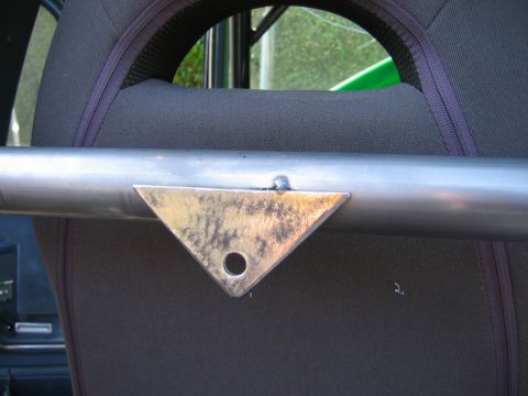 1985 Ford Bronco - A metal bracket is welded to a roll cage tube, positioned near the seat of a vehicle.