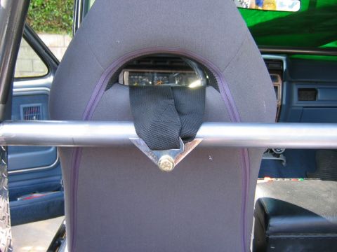 1985 Ford Bronco - The interior of a vehicle shows a roll cage and seatbelt, with dashboard gauges visible in the background.