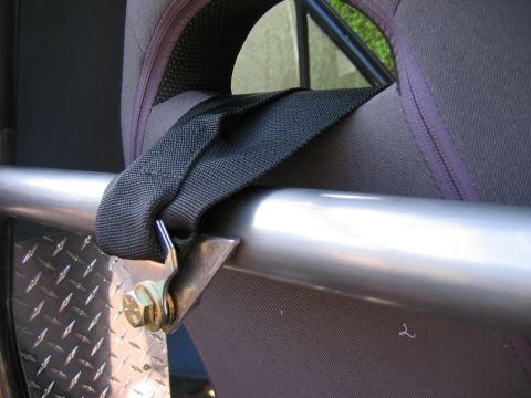 1985 Ford Bronco - Close-up view of a roll cage bar and seatbelt attachment point inside a vehicle.