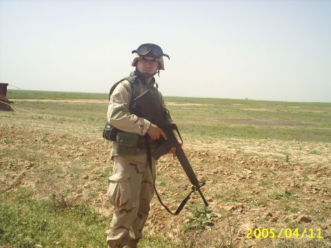1988 Mercury Sable - A soldier stands in a dry, open field, holding a rifle and wearing military gear.