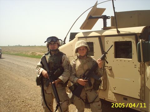 1988 Mercury Sable - Two soldiers pose with their rifles in front of a military vehicle on a dirt road.