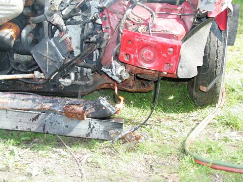 1992 Ford Taurus - Vehicle front end severely damaged, with active fire and exposed engine parts.