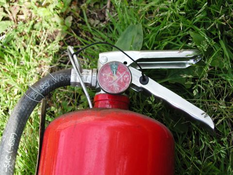 1992 Ford Taurus - A fire extinguisher with a pressure gauge is shown resting on the grass.
