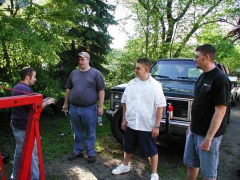 1992 Ford Taurus - A group of men gather around a pickup truck outdoors, with a red engine hoist nearby.