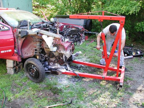 1992 Ford Taurus - An engine is being removed from a damaged red car using a red engine hoist.