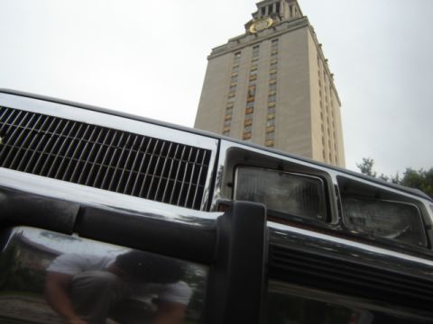 1988 Ford Crown Victoria LTD - A low-angle shot focuses on the front grille and headlights of a vehicle, with a prominent tower in the background.