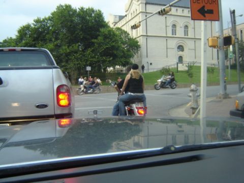 1988 Ford Crown Victoria LTD - A view from inside a vehicle shows several motorcycles and a silver pickup truck at an intersection with a detour sign.