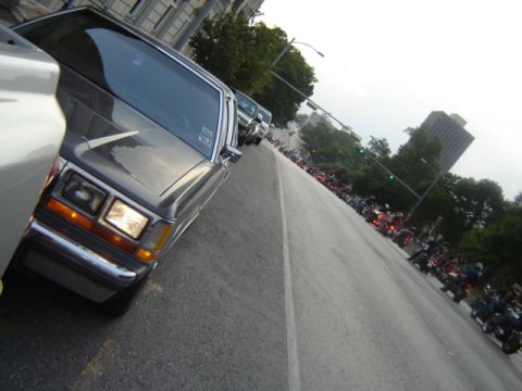 1988 Ford Crown Victoria LTD - A line of motorcycles stretches down the road behind a 1988 Ford Crown Victoria LTD.