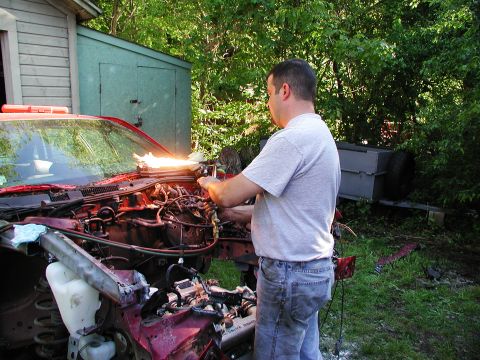 1992 Ford Taurus - A man uses a torch to work on the engine of a 1992 Ford Taurus.