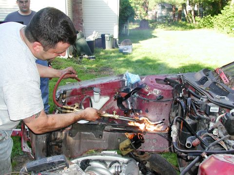 1992 Ford Taurus - Man cutting car frame with torch, another person observes the work.