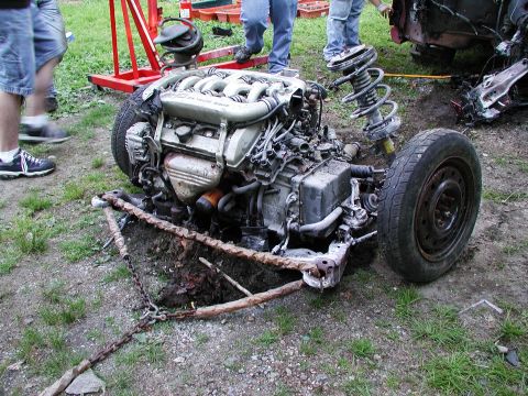 1992 Ford Taurus - Engine and front suspension assembly detached from a vehicle, lying on the ground.