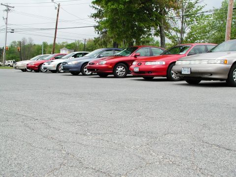 1992 Ford Taurus - Several sedans are parked in a lot, with a tan model in the foreground.