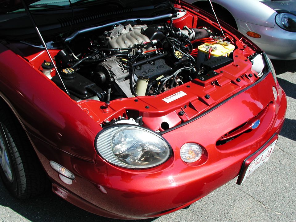 Red 1996 Ford Taurus front with hood open, showing engine and a silver car behind it