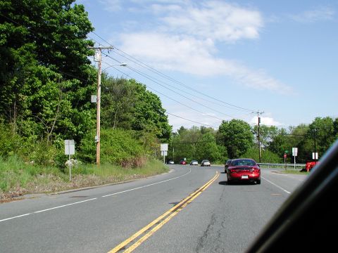 1992 Ford Taurus - A red sedan is seen from behind driving on a road with other vehicles and a clear blue sky.
