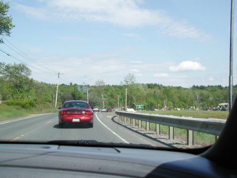 1992 Ford Taurus - A red sedan travels down a highway on a sunny day, with other vehicles visible ahead.