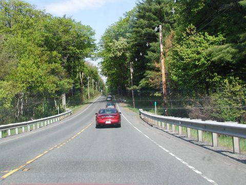 1992 Ford Taurus - A red coupe drives down a tree-lined road, with other vehicles in the distance.