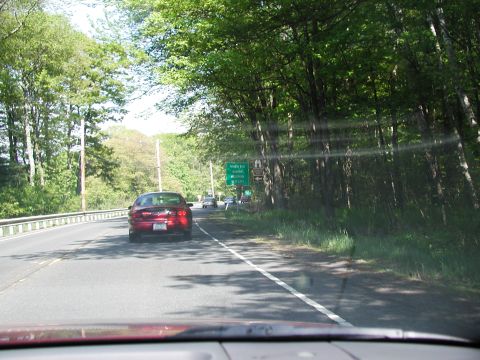 1992 Ford Taurus - A red 1992 Ford Taurus is seen driving on a highway with trees lining the road and other vehicles ahead.
