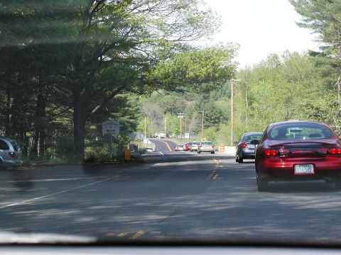 1992 Ford Taurus - A red sedan drives down a two-lane road, with other vehicles visible ahead and to the side.