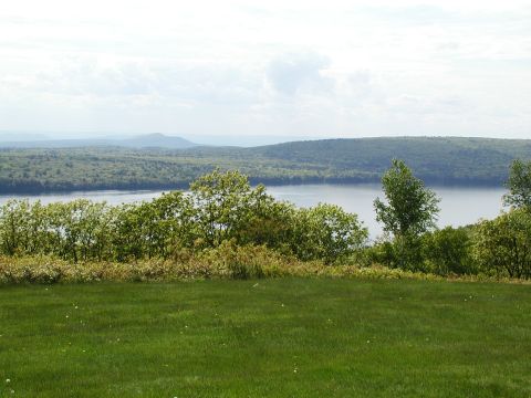 1992 Ford Taurus - Expansive view of a lake and forested hills, captured from a grassy overlook on a hazy day.