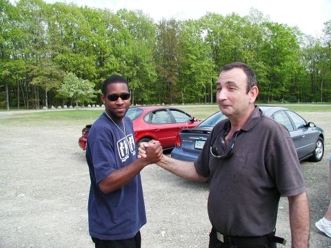 1992 Ford Taurus - Two men share a handshake outdoors with two sedans visible in the background.