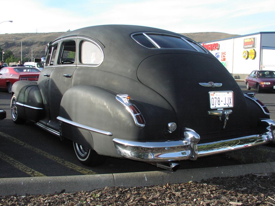 Black sedan with chrome accents and a license plate reading 078-JJX