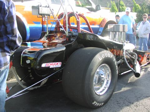 1979 Ford Bronco - A dragster is parked next to a truck with a distinctive orange and blue stripe design.