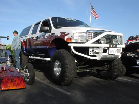 1979 Ford Bronco - Custom lifted SUV with a unique paint job and an American flag flying overhead.
