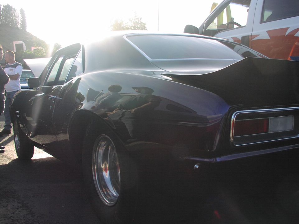 Dark purple 1969 Camaro with a spoiler, parked next to a white truck
