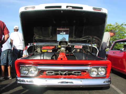 1979 Ford Bronco - A red GMC truck is displayed with its hood open, its powerful engine and prominent air intake scoop.