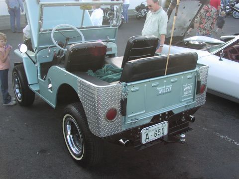 1979 Ford Bronco - A light blue Willys jeep is parked next to a white car, with people milling around.