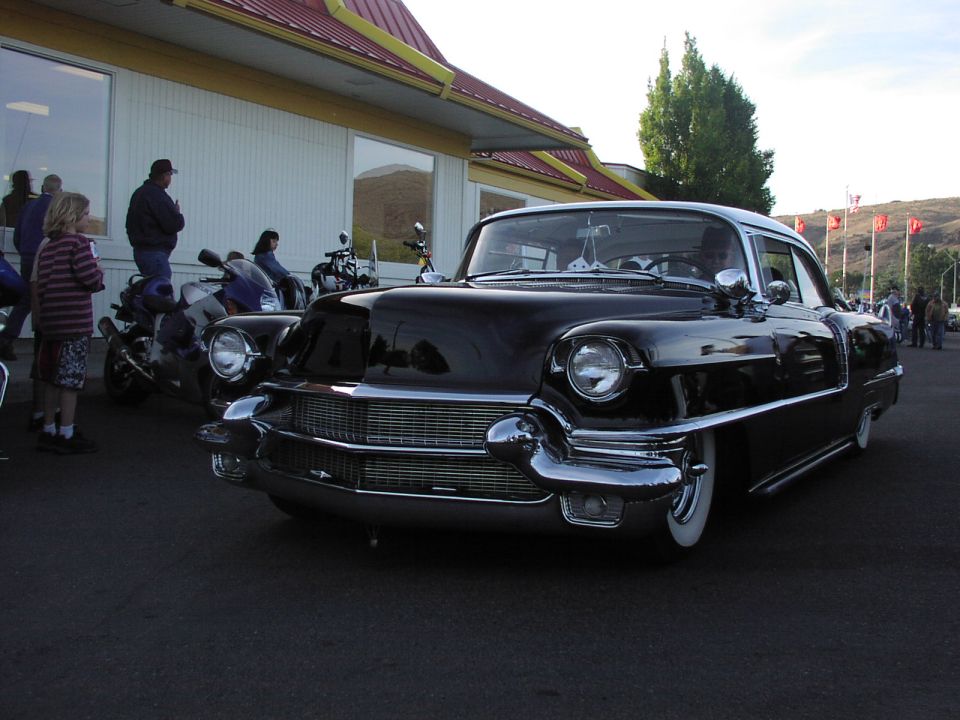 Black classic car with chrome grille and whitewall tires parked outside