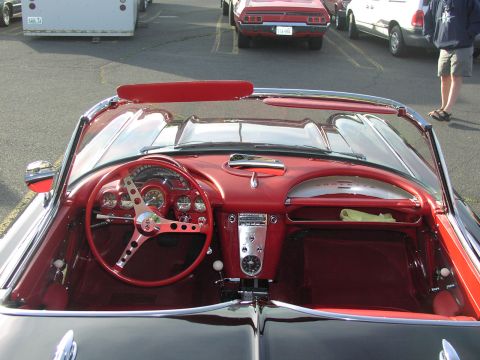 1979 Ford Bronco - The interior of a vintage convertible features a red dashboard and steering wheel with chrome accents.