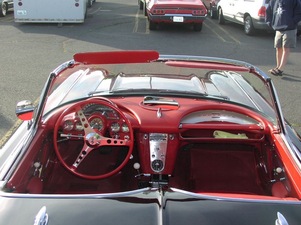 Red interior of a classic car, showing steering wheel, dashboard, and radio