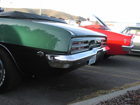 1979 Ford Bronco - Rear view of a green 1969 Pontiac Firebird convertible parked next to a red car.