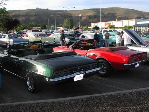 1979 Ford Bronco - Two Pontiac Firebird convertibles from 1969 are parked side-by-side at an outdoor car show.