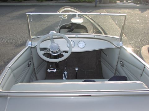1979 Ford Bronco - The interior of a classic convertible shows a large steering wheel, two dashboard gauges, and light-colored upholstery.