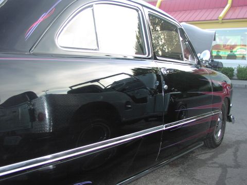 1979 Ford Bronco - A black classic car with custom pinstripes is parked outside a building. A Jeep is reflected in its side panel.