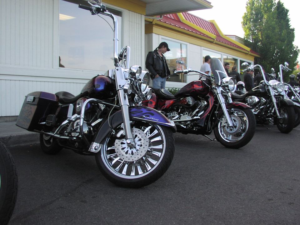 Several custom motorcycles parked in a row, one in foreground has purple and black paint
