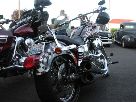 1979 Ford Bronco - A motorcycle with a checkerboard design is parked next to another motorcycle and two classic cars.