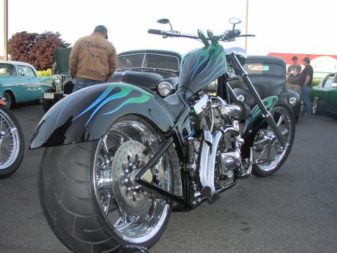 1979 Ford Bronco - A custom chopper motorcycle with a wide rear tire and chrome accents is displayed alongside vintage automobiles.