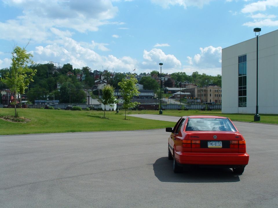 Red Volkswagen Jetta parked on asphalt, rear view. License plate reads FMG-8132