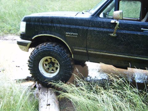 1988 Ford Bronco - This 1988 Ford Bronco navigates a muddy obstacle course, with its tires on a log.