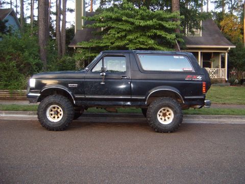 1988 Ford Bronco - This black 1988 Ford Bronco features off-road tires and a lifted suspension, seen from the side.